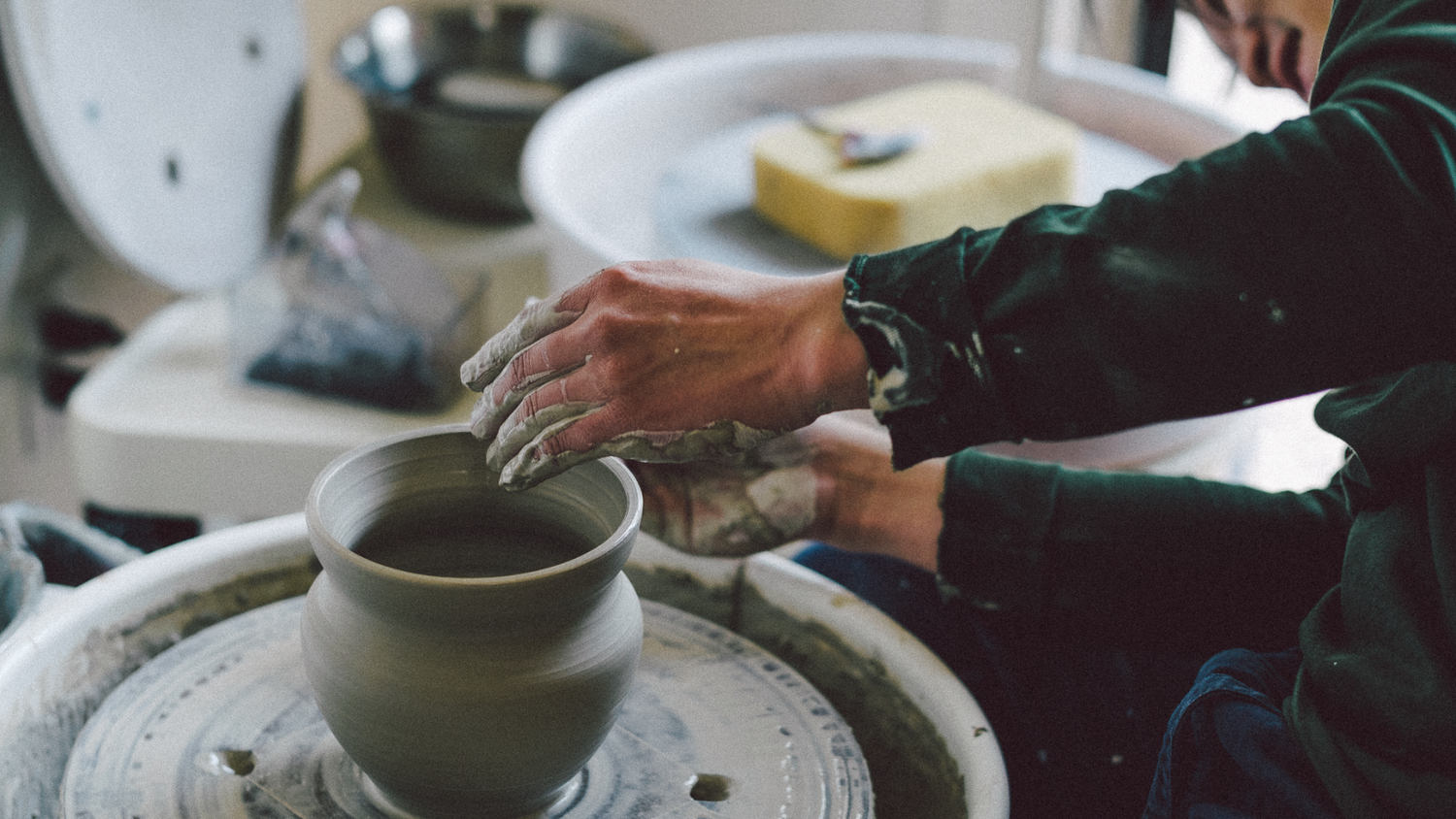 a person's hands making a clay pot